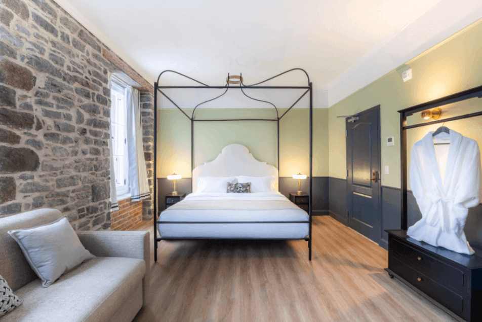 Acadia Hotel Quebec City canopy queen room with exposed stone wall, sofa and robe