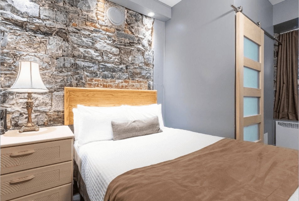 Guest room with exposed stone wall at Hotel Jardin du Gouverneur Quebec City in Old Quebec